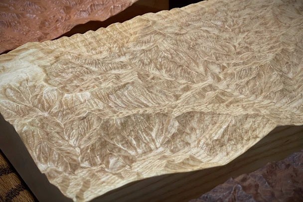 Light maple wood carving of a mountain range, side view
